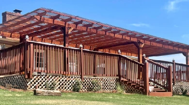 A pergola attached to the patio on the side of a home.